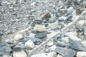 Atmospheric image of stone cairns carefully stacked along a remote roadside in Ladakh — perfect...