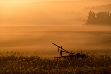 Fototapeta premium Landschaft mit umgestürzten Hochsitz mit abendlicher Sonnenuntergangsstimmung und Nebel