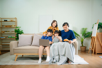 Asian Little children bonding with parents on sofa at home and using tablet.