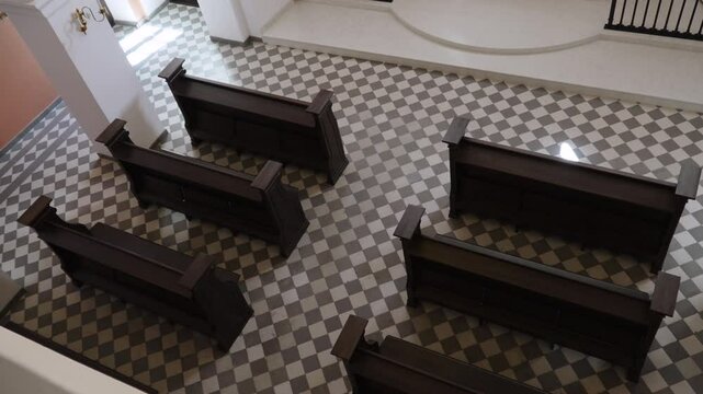 Top view of 6 wooden benches in modern church hall with checkered tiles. Interior of minimalist protestant church without people.