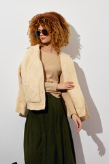 Fashion model wearing stylish oversized cardigan and sunglasses, showcasing a trendy winter outfit...