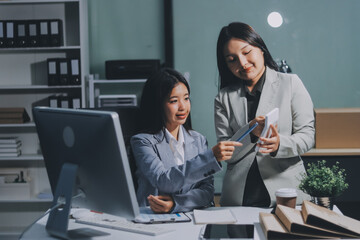 Asian Businesswoman Using laptop computer and working at office with calculator document on desk, doing planning analyzing the financial report, business plan investment, finance analysis concept.