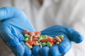 bunch of different pills in the hands of a doctor in blue gloves close-up background pharmacy