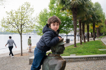 Child plays on statue in a park by the river