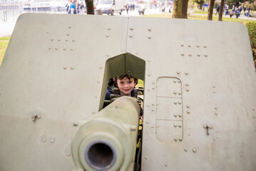 Child smiles while peering through military weapon