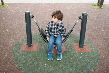 Child enjoying playground swing on a cloudy day