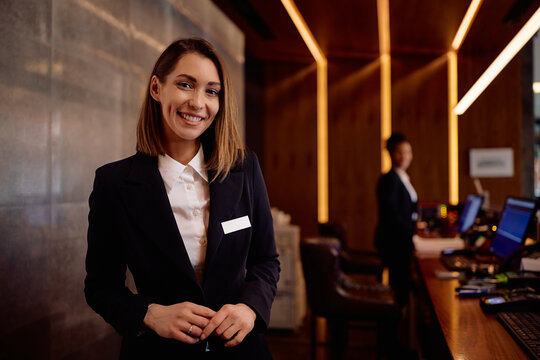 Happy female receptionist working in hotel and looking at camera.