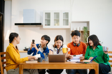 Young Asian adults collaborating on laptops and tablets in a cozy workspace, embodying teamwork, c