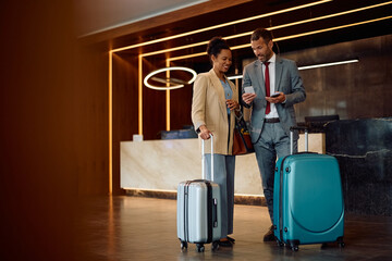 Happy black businesswoman and her coworker staying in at hotel on their business travel.