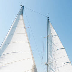 Fototapeta premium Close-Up of White Sails Against Clear Blue Sky – Minimalist Nautical Scene on a Sunny Day at Sea