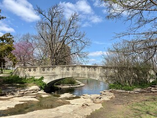 Stone bridge over creek surrounded by early spring trees at Eden Park