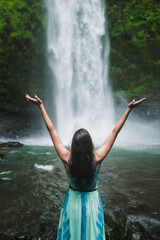 Woman with Open Arms Facing Waterfall, Surrender, Healing and Connection with Nature.