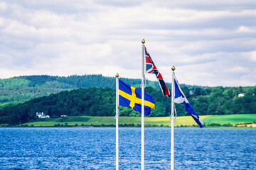Fototapeta premium Swedish Great Britain and Scottish flag on the seashore