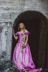 Beautiful girl with long hair braided in a braid, in corset and magnificent pink dress.