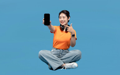 Enthusiastic woman takes a selfie while sitting in a meditative yoga pose against a blue backdrop