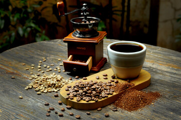 
A traditional hand coffee grinder is surrounded by whole coffee beans, ground coffee, and a rustic...