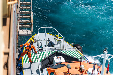 Aerial, top view on the pilot boat - deckhand preparing safe way for navigational pilot to enter...