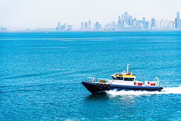 Pilot boat sailing across calm, blue waters on her way to assist a cargo ship during arrival maneuverings to the port terminal. Jebel Ali - United Arab Emirates.  