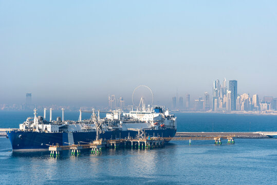 Tanker ship, LNG carrier moored in the gas terminal in the port of Jebel Ali. City skyline of Dubai visible on the horizon.