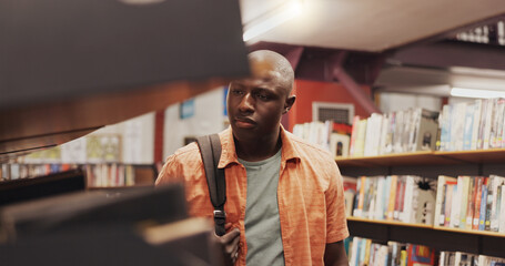 Man, student and shelf with books in library for choice, textbook search and studying for exam....