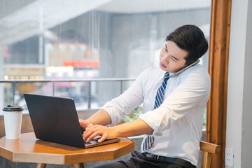 Young professional multitasking with laptop and mobile working in a bright modern setting