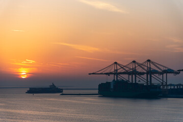 Beautiful sunset silhouette of ships and gantry cranes in the port of Jebel Ali. Golden hour in the...