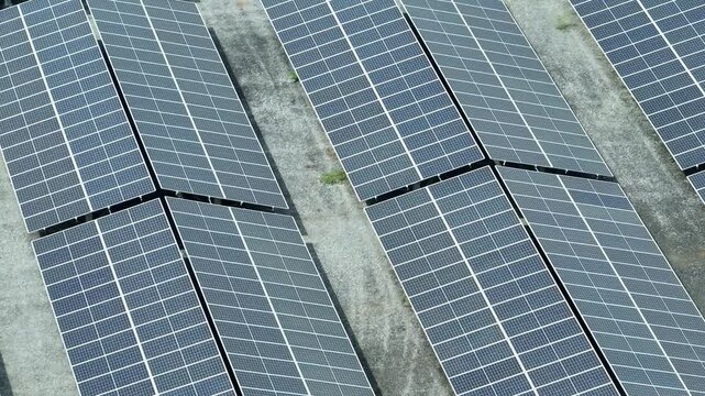 The aerial view showcases a vast array of solar panels aligned meticulously to capture sunlight, symbolizing the shift towards sustainable and eco-friendly energy production.
