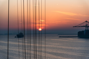 Obstructed view (by gantry crane wires) of the port sunset, silhouette of the ship and gantry...