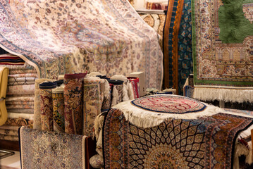 Interior of a shop filled with Iranian silk carpets in various colors and intricate patterns, showcasing the richness of traditional craftsmanship.
