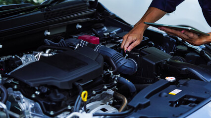 Mechanic in work gloves repairs car engine in auto repair shop. Auto mechanic checks vehicle with...