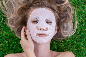 Close up of woman's face with cosmetic face mask in grass. Spa, healthy, naturally. Healthy...