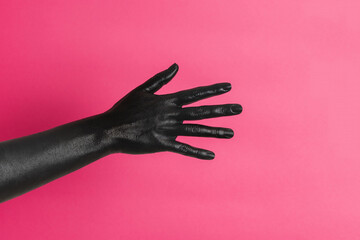 Black painted elegant woman's hand on her skin gesticulates on pink background. High Fashion art concept