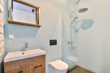 Stylish bathroom design featuring a glass shower enclosure, minimalist furnishings, and soothing blue wall colors. Ideal for contemporary home aesthetic.