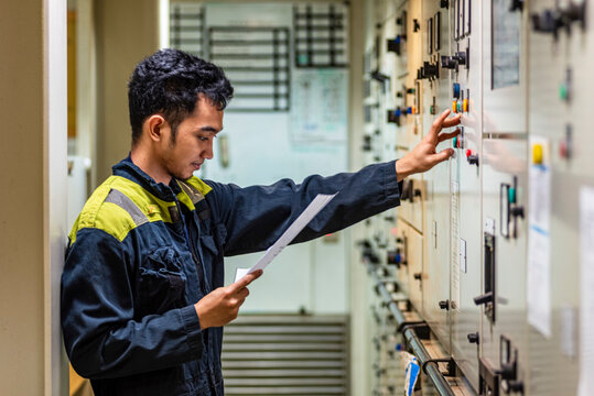 The marine engineering officer stands before the control panel of the ship&rsquo;s pumps, fully focused on activating another piece of machinery. 