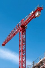 A single, powerful crane stands tall, its shadow cast upon the developing building below against the clear blue sky - Engineering Working work blue sky