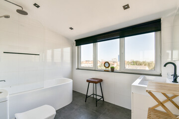 A contemporary bathroom featuring large windows that provide ample natural light, paired with minimalist fixtures and neutral tones for a clean aesthetic.
