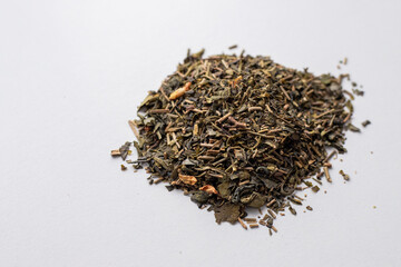 Green tea dry petals with jasmine buds. Dried herbal drink. Green Chinese tea. Top view on white background. Tea drinking. Pile of green herbs and leaves