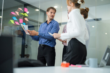 Team members engage in brainstorming session around sticky notes in modern office setting during...