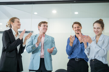 Team celebrates project success with applause in a modern office setting during a bright afternoon meeting