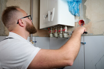 Plumber Install a Boiler. Professional engineer installing gas boiler at home and checking the...