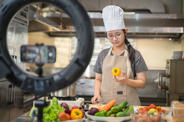 A female chef broadcasts her cooking knowledge live on a social media app on her mobile phone.