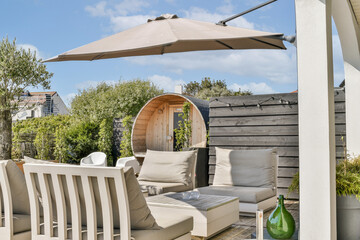 A chic outdoor lounge area featuring modern furniture, a wooden structure, and an elegant canopy. Perfect for relaxation in a serene environment with natural greenery.