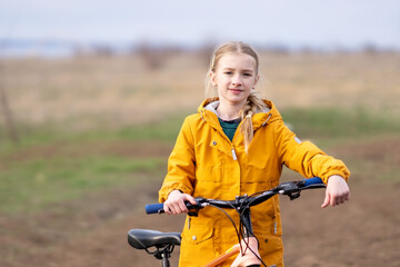 Obraz premium Portrait of a girl on a bicycle. Portrait of a girl in warm clothes on a bicycle outside the city. Bicycle rides