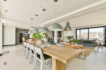A stylish interior featuring an open layout with a spacious dining area, contemporary furniture, and large windows allowing natural light.