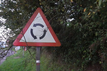 Roundabout Warning Sign Near Overgrown Foliage