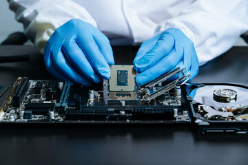 The technician is putting the CPU on the socket of the computer motherboard. electronic engineering...