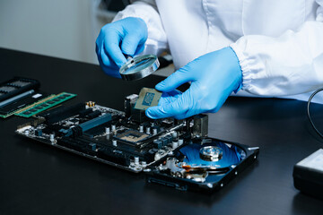 Obraz premium The technician is putting the CPU on the socket of the computer motherboard. electronic engineering electronic