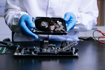 Hard disk drive on the technician's desk and a computer motherboard as a component. the concept of data, hardware