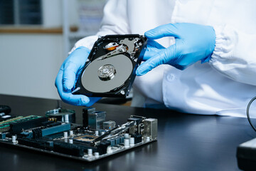 Obraz premium Hard disk drive on the technician's desk and a computer motherboard as a component. the concept of data, hardware