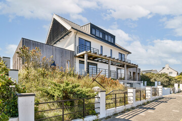 Fototapeta premium A stunning modern house featuring sleek lines and large windows, elegantly set amidst lush greenery and neat landscaping, exemplifying contemporary living.